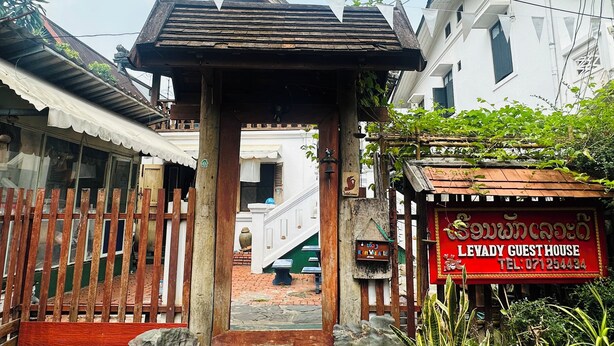 Una estructura de madera tradicional con un letrero que dice 'Levady Guest House' y un número de contacto.