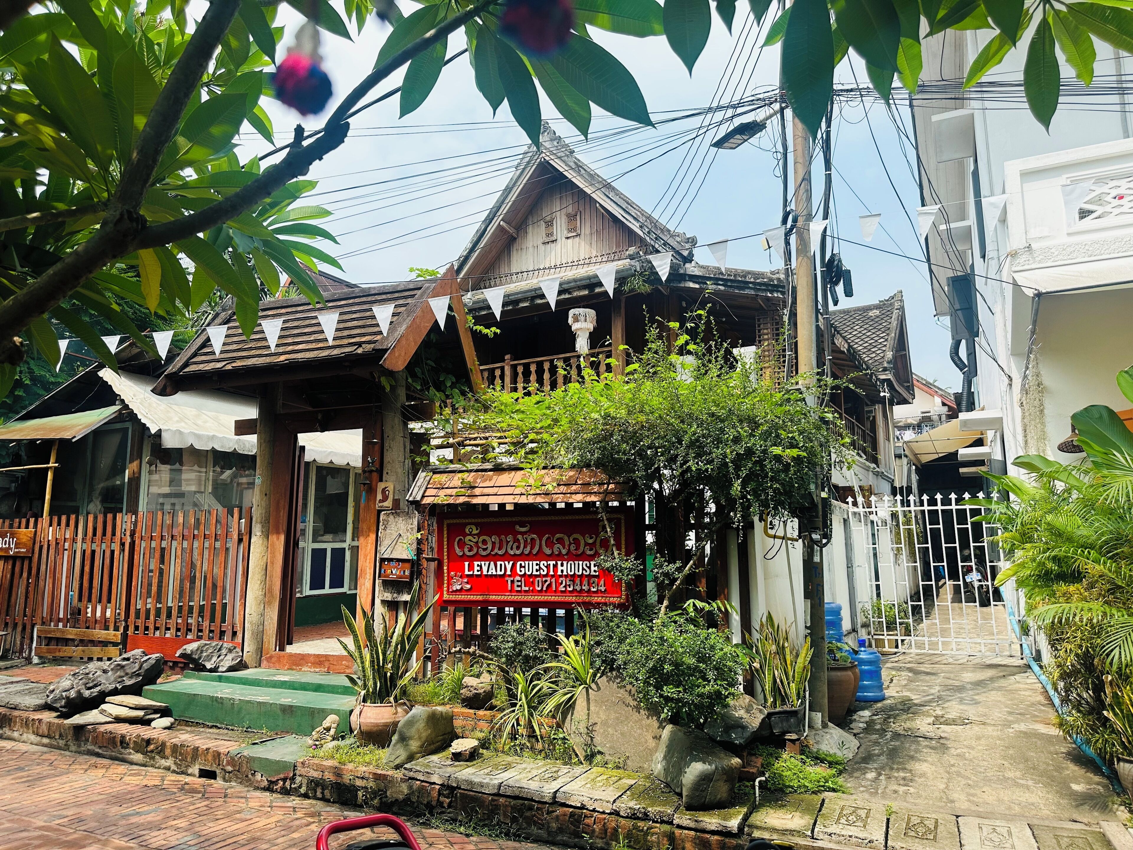 A traditional wooden building with a sign for 'Levad Guest House' and a gated entrance.