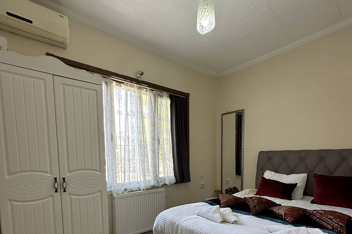 A bedroom with a bed, a wardrobe, a radiator, and a ceiling light.