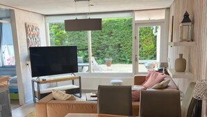 Un saló modern amb un televisor gran, una taula de dinar i un sofà.