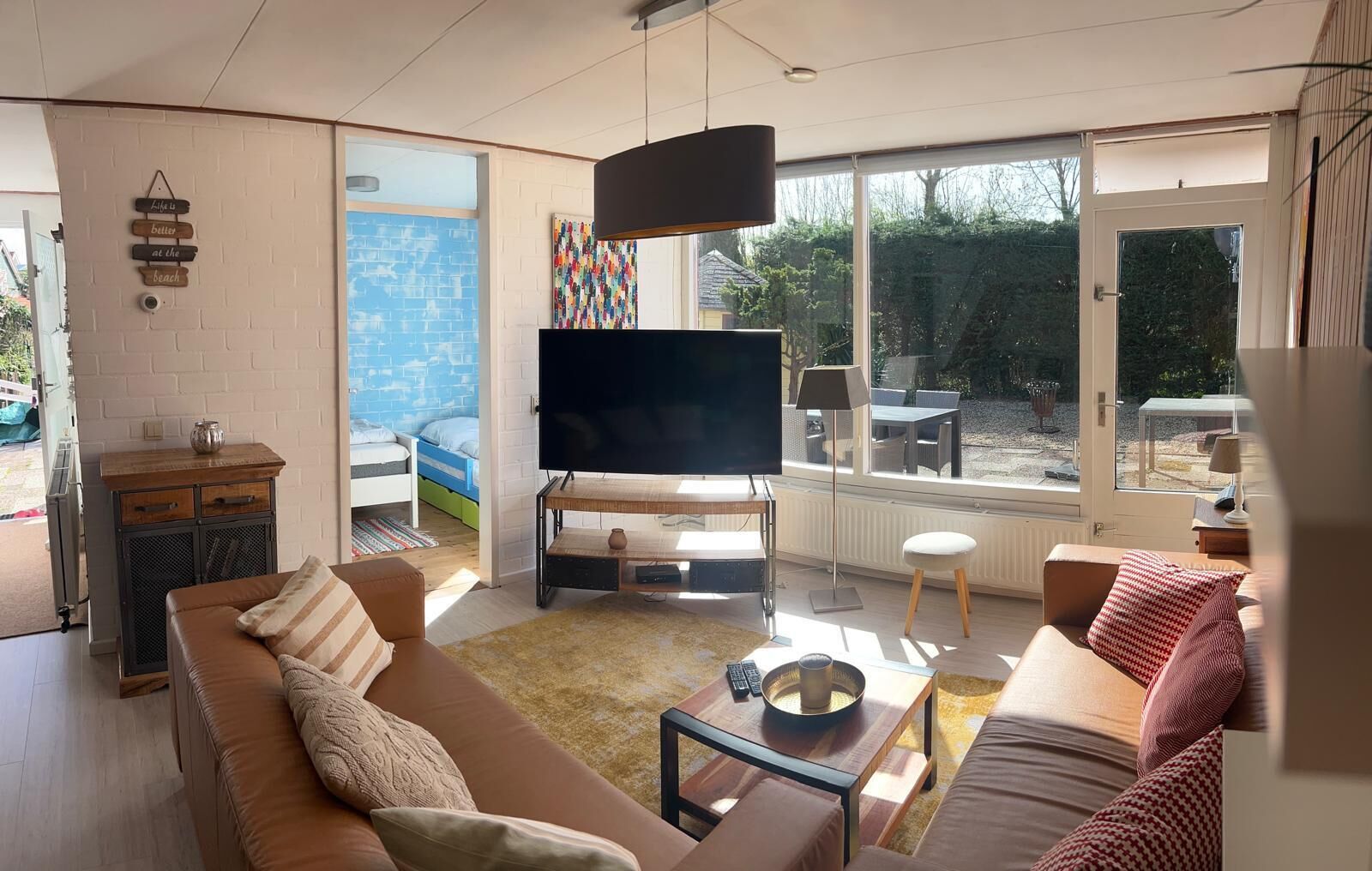 Un salon moderne doté d’un grand téléviseur à écran plat, d’un canapé, d’une table basse et d’un coin repas avec une table et des chaises.