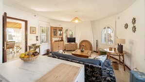A cozy living room with a sofa, a dining table, and a TV.