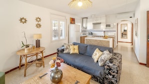 A living room with a sofa, coffee table, and a dining area with a kitchen in the background.
