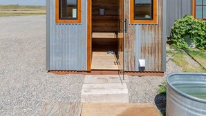 Une petite cabane rustique avec une porte en bois et deux fenêtres.