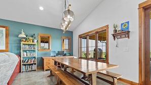 Une cuisine spacieuse avec une grande table en bois, une bibliothèque et un luminaire suspendu.