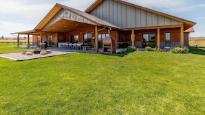 Un bâtiment moderne doté d’un patio couvert, d’un espace extérieur aménagé pour s’asseoir et d’un barbecue.