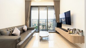 Ein modernes Wohnzimmer mit Ledersofa, Couchtisch, Flachbildfernseher und Stadtblick durch große Fenster.