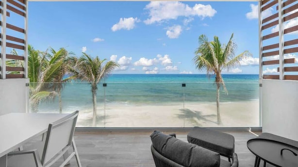 Ein Balkon mit Blick auf den Strand, Palmen und das Meer.