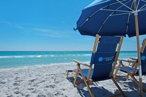 Una silla de playa con una sombrilla azul y un logotipo en el respaldo.