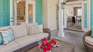 A cozy living room with a sofa, a coffee table with a vase of red roses, and a dining area in the background. - Pet & Family Friendly, Walk or Tram 2 Private Beach Access Pavilion, Pools, Tennis - Emerald Shores (Miramar Beach)