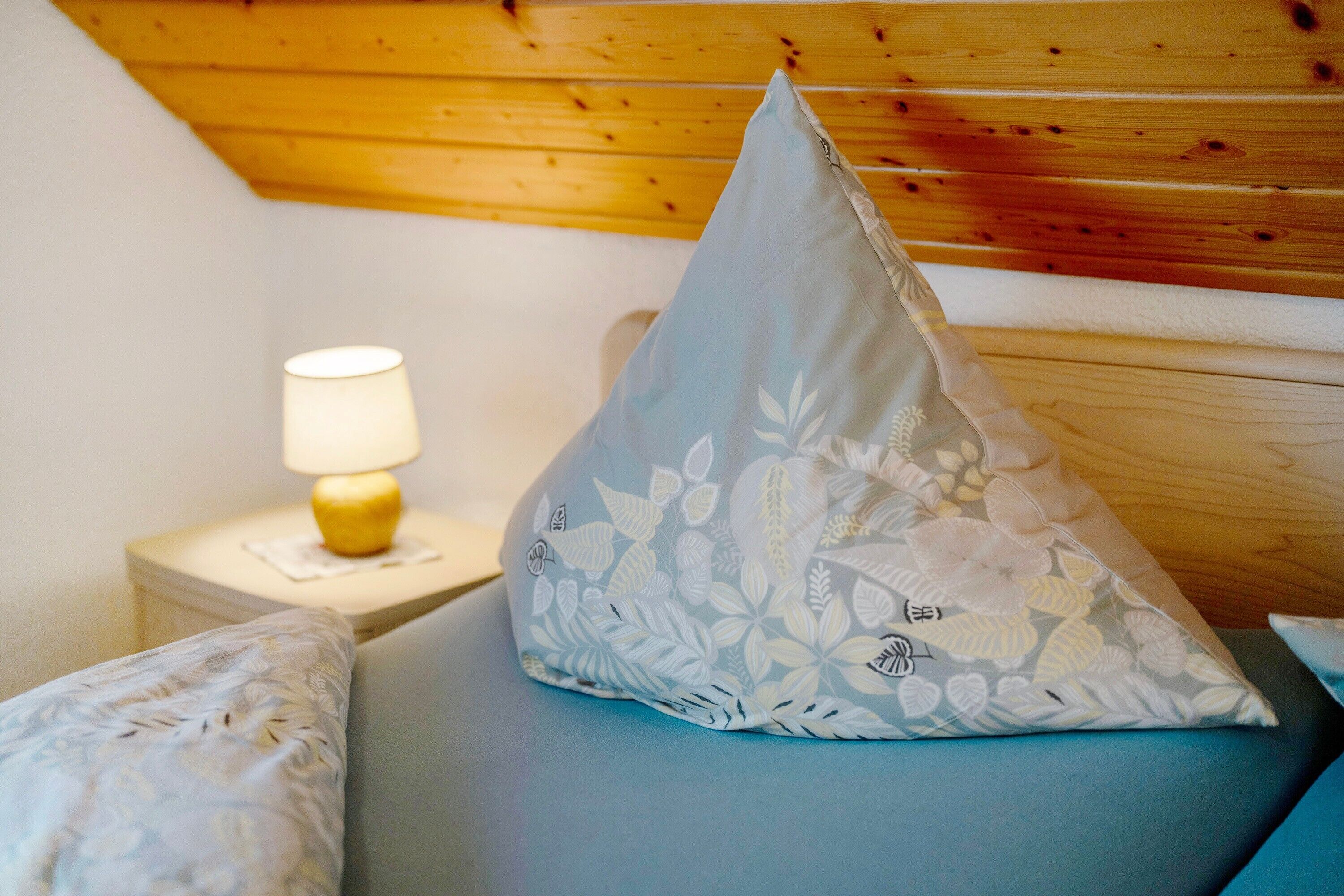 A bed with a pillow, a bedside lamp, and a wooden headboard.
