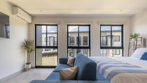 Ein modernes Schlafzimmer mit einem großen Bett, einem blauen Sofa und einer Topfpflanze.