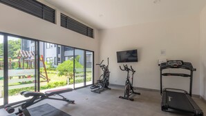 Ein Fitnessstudio mit Trainingsgeräten, großen Fenstern und Blick auf einen Spielplatz.