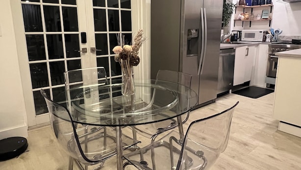 A modern kitchen with a glass dining table, stainless steel appliances, and a white door. - Newly renovated home near Hard Rock Stadium and major highways! (Miami Gardens)