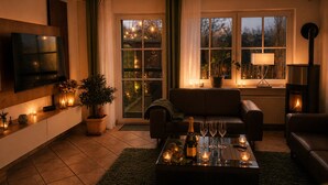 Ein gemütliches Wohnzimmer mit Fernseher, Sofa, Couchtisch mit Getränken und Kamin.