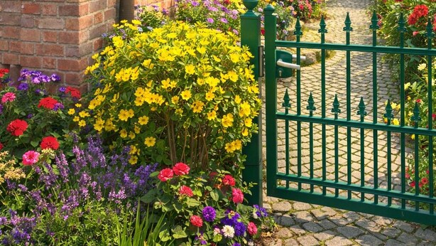 Ein Backsteinhaus mit grüner Markise, einem Fenster und einem Garten mit bunten Blumen.