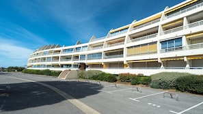A multi-story hotel with balconies, a parking lot, and a clear sky.