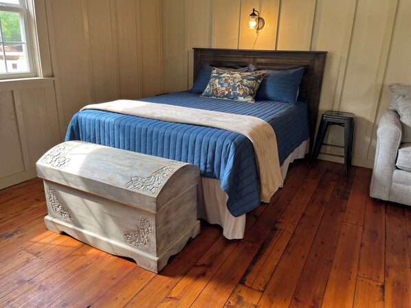 A bedroom with a wooden bed, a nightstand, a bench, and a small stool. - Tack Room @ Redemption Ranch: Grill, Deck, Peaceful, Unique, Comfortable (Marionville)