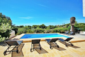 Un espace piscine avec des chaises longues et un pilier décoratif.