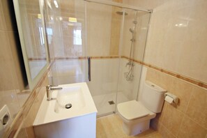 Une salle de bain moderne avec une douche à parois de verre, un lavabo blanc et des toilettes.