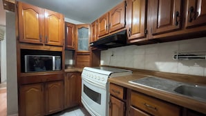 A kitchen with wooden cabinets, a built-in oven, and a stainless steel sink. - House Near The Santiago River (San Luis Potosi)