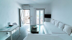 A hotel room with a bed, a desk, a glass coffee table, and a view of the sea through the door. - Apartment with Pool & Shared Infinity Pool, Sea View,  Pool Bar, Gym (C965+8J Mykonos, Řecko)