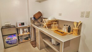A compact kitchen with a refrigerator, microwave, sink, and a small trash bin. - Aashvi Cozy Cabin (Lapu-Lapu)