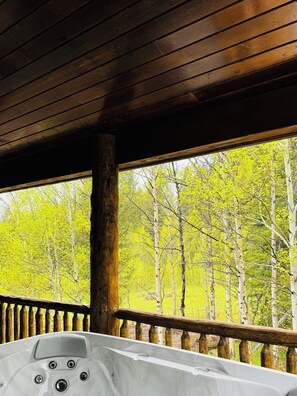 A wooden deck with a hot tub and a view of a forest.