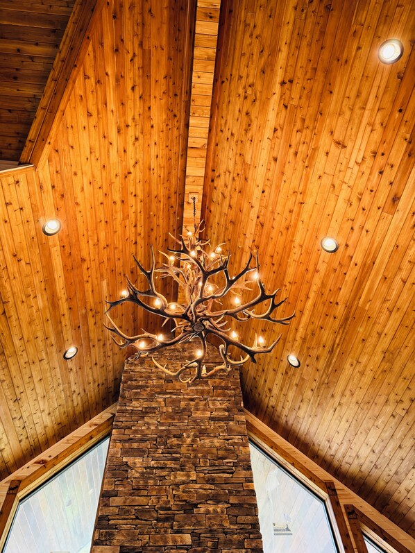 Eine Holzbalkendecke mit einer Chandelüstere und einem Steinofen.