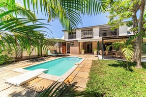 Une maison à deux étages avec une piscine, du mobilier d’extérieur et un espace patio.