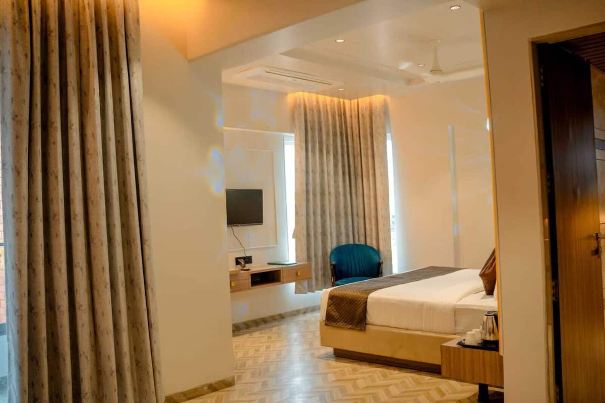 A modern hotel room with a large bed, a desk with a computer, a chair, and a TV mounted on the wall.