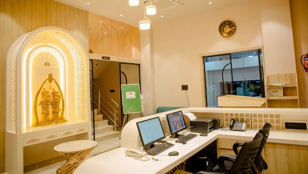 A modern office with a reception desk, computers, and a staircase leading to an upper level. - Narayani Executive (Tuljapur)