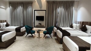 A hotel room with two beds, a TV, and a small table with chairs. - Narayani Executive (Tuljapur)