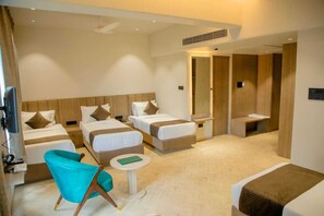 Two single beds with wooden headboards, a small table, and a blue armchair.