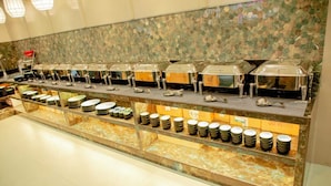 A buffet setup with multiple serving stations, each equipped with a variety of dishes and utensils. - Narayani Executive (Tuljapur)
