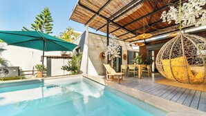A swimming pool with a wooden deck, a hanging chair, and a covered seating area. - Villa Latrille - Ermitage les bains - near the beach  (Saint-Paul)