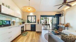 A modern kitchen with white cabinets, a dining area with a table and chairs, and a ceiling fan. - Villa Latrille - Ermitage les bains - near the beach  (Saint-Paul)