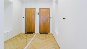 A hallway with two wooden doors, white walls, and a wooden herringbone floor. - Lumina 4-room apart near Pałac Kultury (Warsaw)