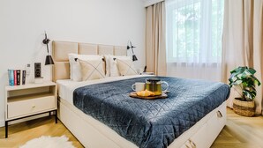 A modern bedroom with a large bed, bedside tables, a nightstand, and a window with curtains. - Lumina 4-room apart near Pałac Kultury (Warsaw)