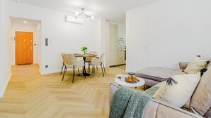 A modern living room with a sofa, a coffee table, and a dining area with chairs and a table. - Lumina 4-room apart near Pałac Kultury (Warsaw)