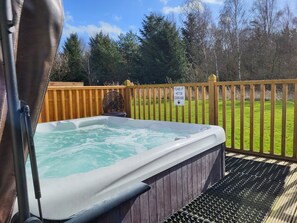 A hot tub with a wooden deck and a sign instructing to lift the hot tub cover.