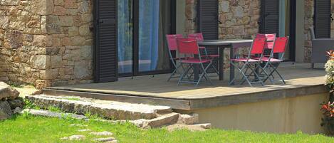 A stone building with a pool, outdoor seating, and a wooden deck.