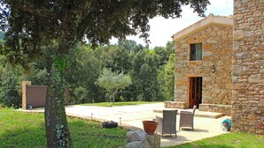Un bâtiment en pierre doté d’un patio, d’un espace extérieur aménagé avec des sièges et d’un arbre.