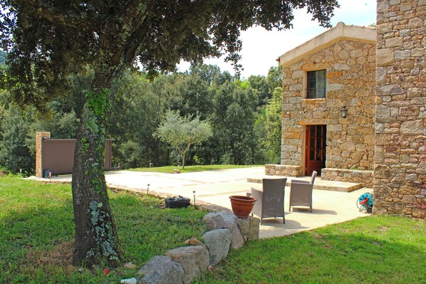 A stone building with a patio area, outdoor seating, and a tree.