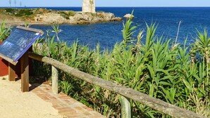 A coastal view with a stone tower, a wooden fence, and a signboard. - Apartment Ayla by Interhome (Casares)