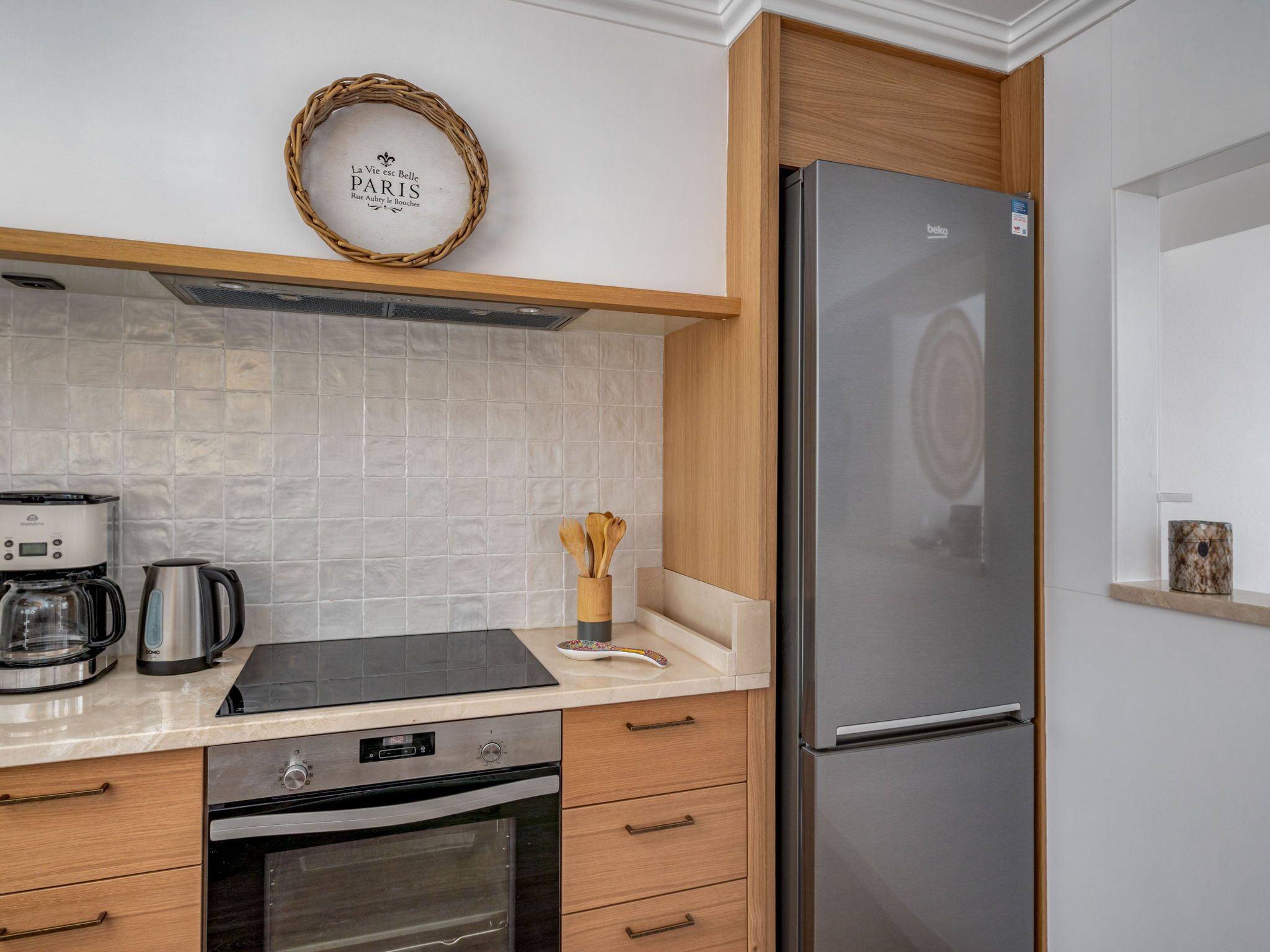 Una cucina moderna con frigorifero in acciaio inossidabile, macchina del caffè, bollitore e mobili in legno.