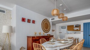 A dining area with a round table, wicker chairs, and hanging rattan light fixtures. - Apartment Ayla by Interhome (Casares)