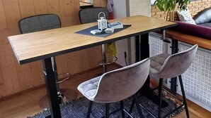 A dining area with a wooden table, two chairs, a small rug, and a potted plant.