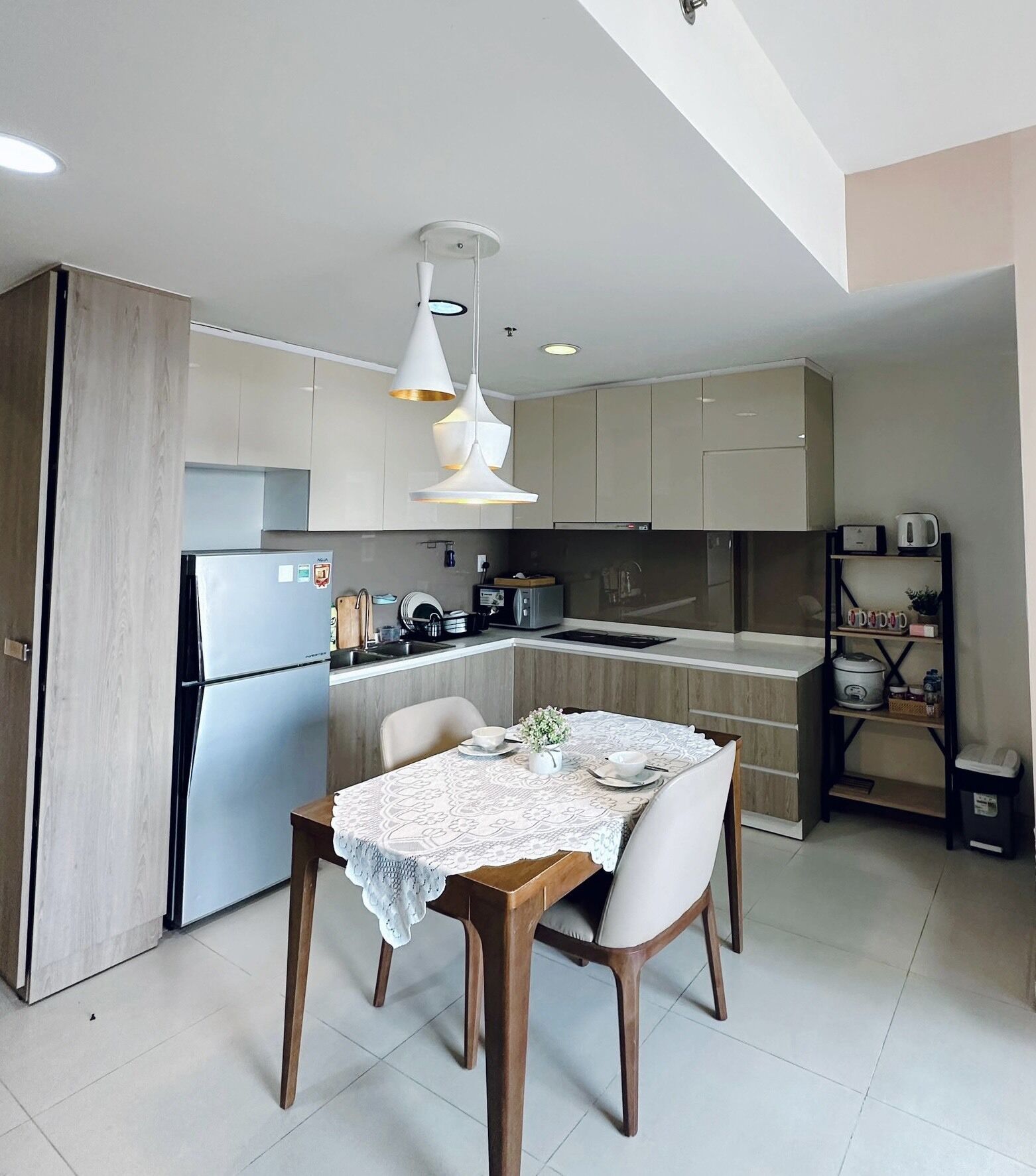Una cocina moderna con comedor, que incluye una mesa de madera, sillas e iluminación colgante.