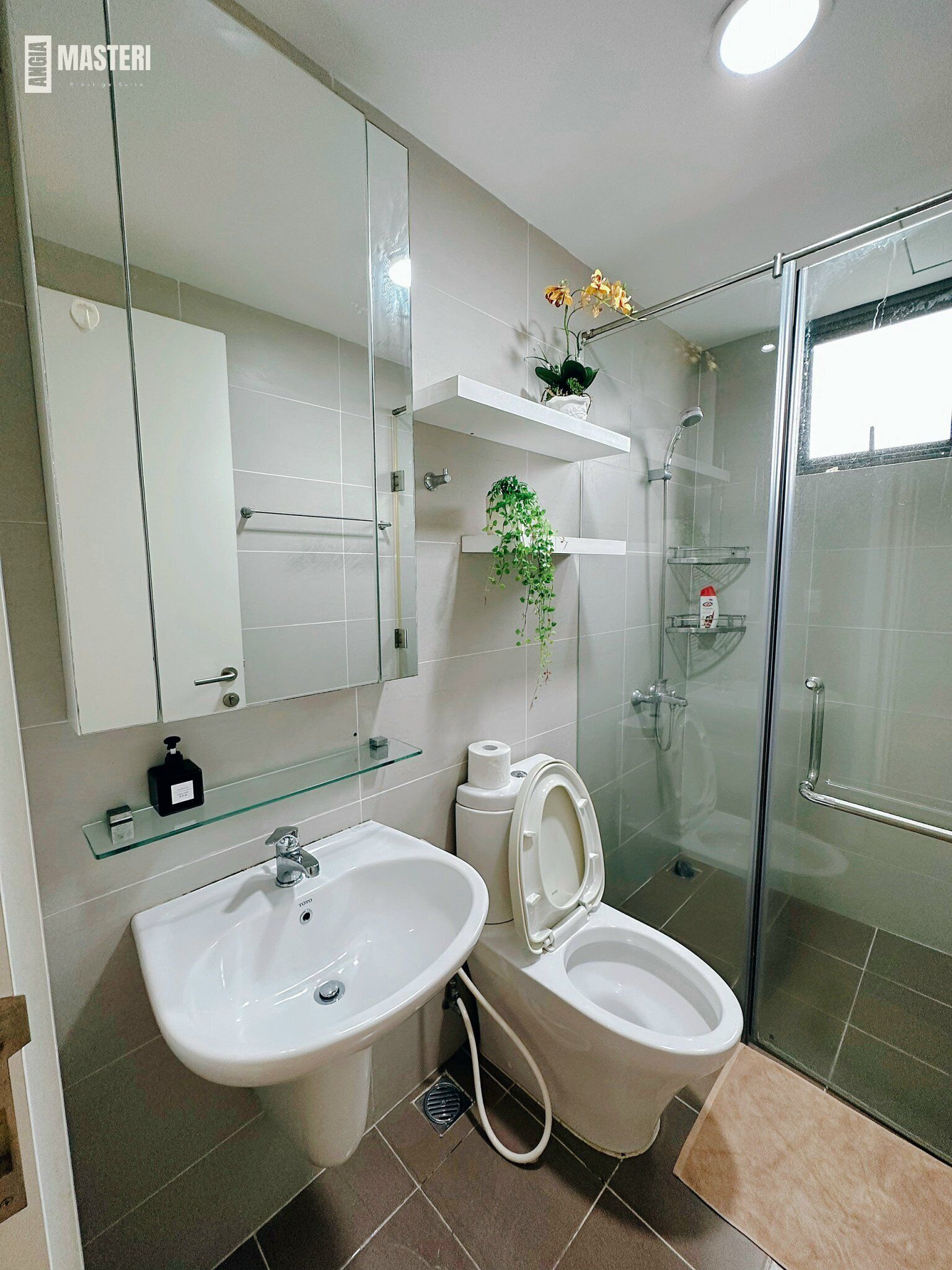 A modern bathroom with two sinks, a toilet, a glass shower enclosure, and a mirror above the sink.